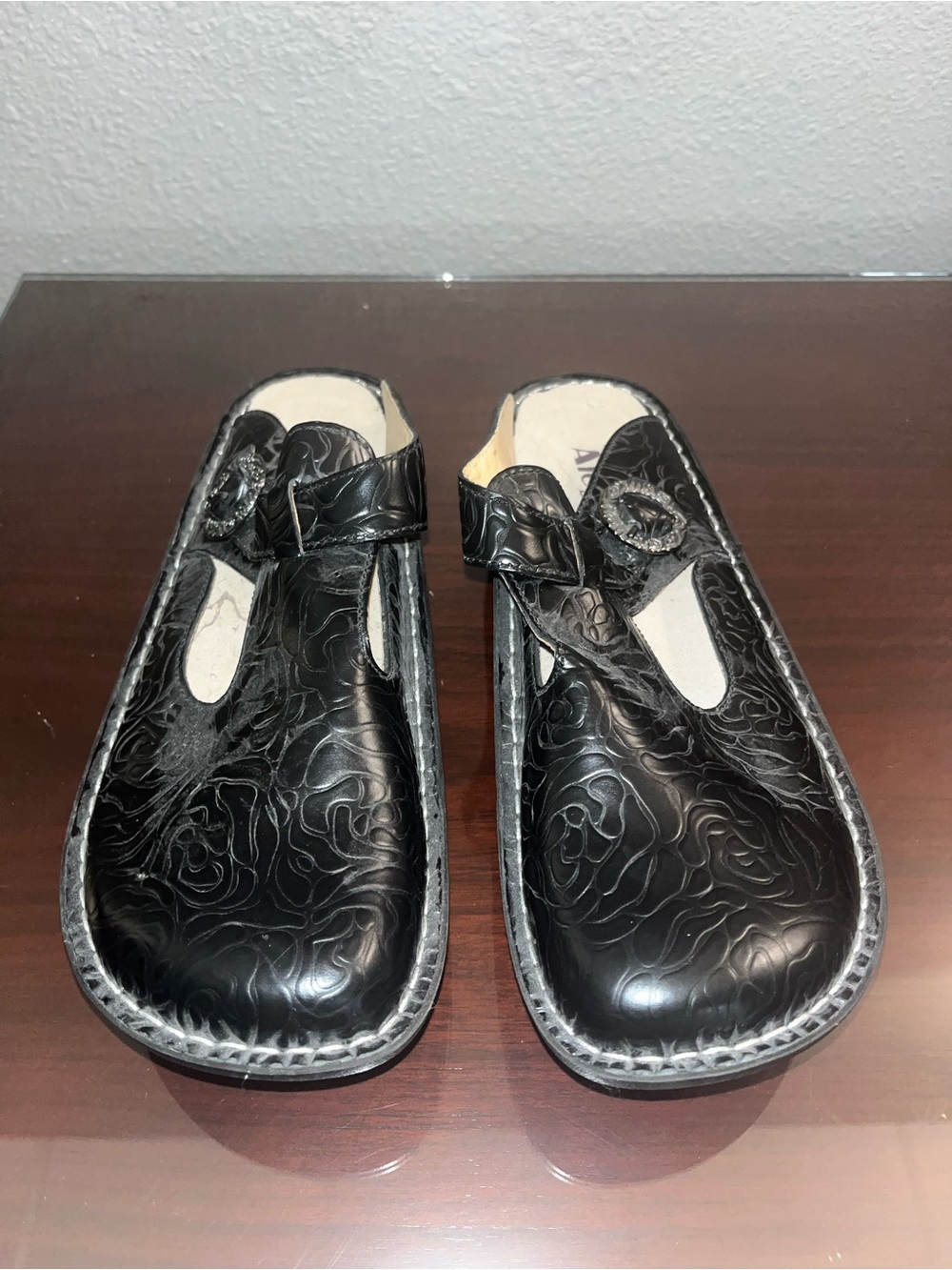 Alegria Black Floral Embossed Slip-On Clogs with Buckle Detail